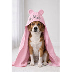 Cachorro sentado com toalha pet rosa personalizada com o nome Mel e capuz de orelhinhas